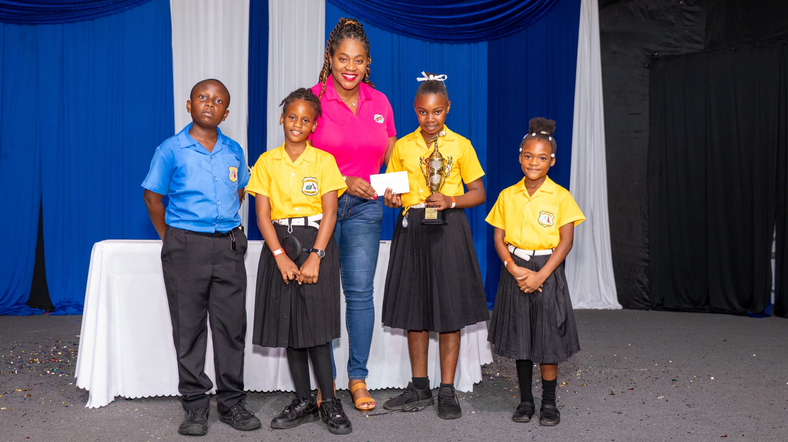 RUBIS’ Areen Lewis presents students of St. Dominic R.C. School with their third-place trophy and prize at the inaugural Grenada Broadcasting Network (GBN) Primary Schools Carol Competition.